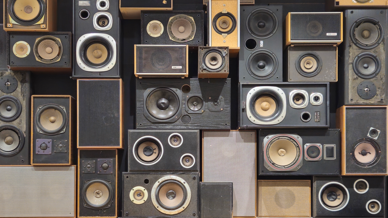 A collection of vintage speakers and audio equipment arranged in a grid pattern against a dark background