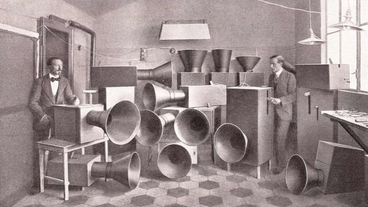 Luigi Russolo and Ugo Piatti standing with multiple Intonarumori noise instruments in a laboratory in Milan, 1913